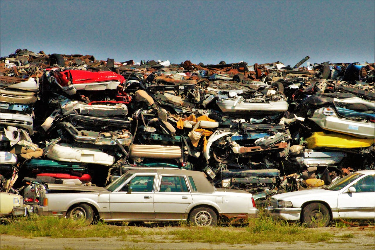 A large stack of disposed vehicles in an outdoor junkyard.