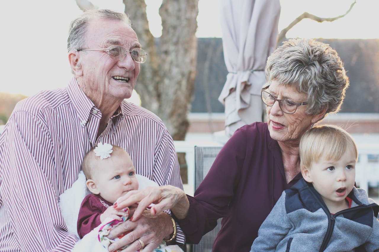 Grandparents spending joyful moments with their grandchildren in an outdoor setting, captured candidly.